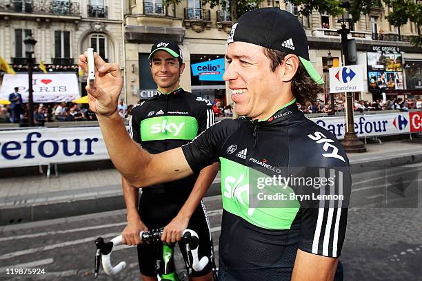 Xavier Zandio watches teammate Rigoberto Uran of Team SKY take a photo after the twenty first and final stage of Le Tour de France 2011, from Creteil...