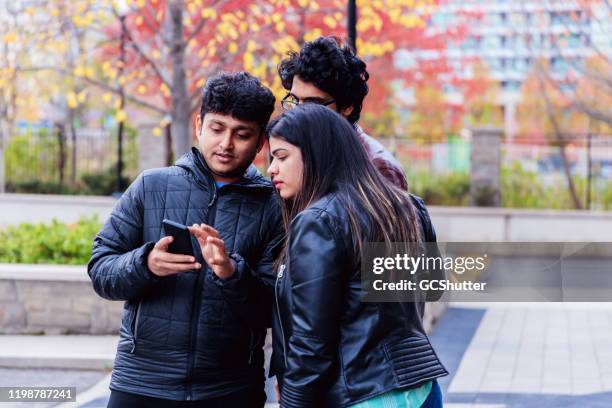 friends checking our latest social media post using a smartphone - long weekend canada stock pictures, royalty-free photos & images