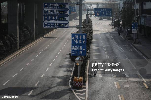 Man drags a handcart across a road on February 5, 2020 in Wuhan, Hubei province, China. Flights, trains and public transport including buses, subway...