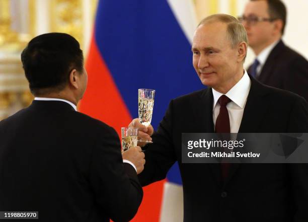 Russian President Vladimir Putin holding a glass of champaigne toasts with Chinese Ambassador Zhang Hanhui during the ceremony for President Putin to...