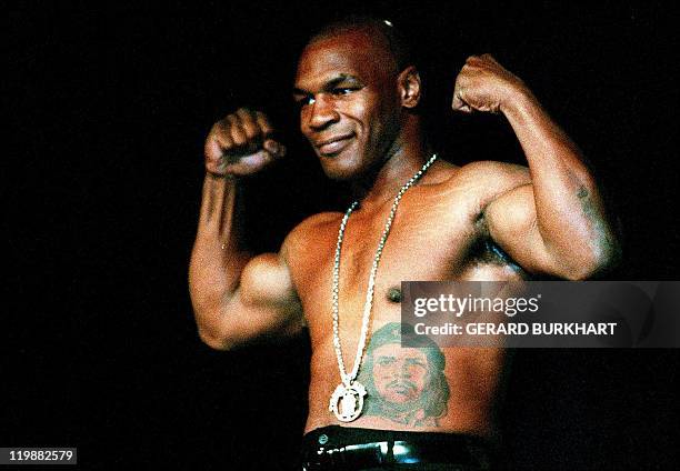 Boxer Mike Tyson shows his fitness for the ring by climbing onto a table and flexing his muscles for reporters at a news conference in Beverly Hills...