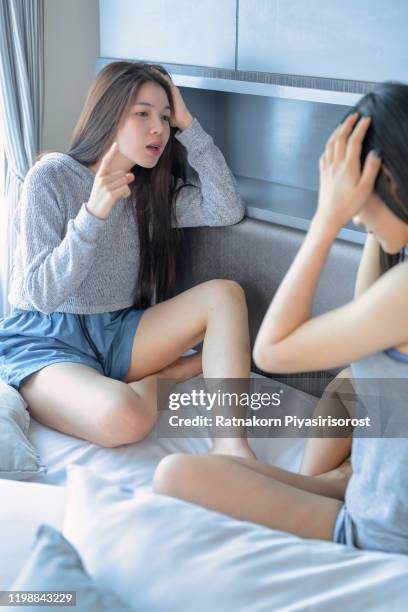 young teen asian couple having arguments and problems in bed. asian beauty sad girl was comforted by a girl friend. people and social issues problem concept. lifestyle and friendships theme. lesbian and family theme. - teen lesbian stockfoto's en -beelden