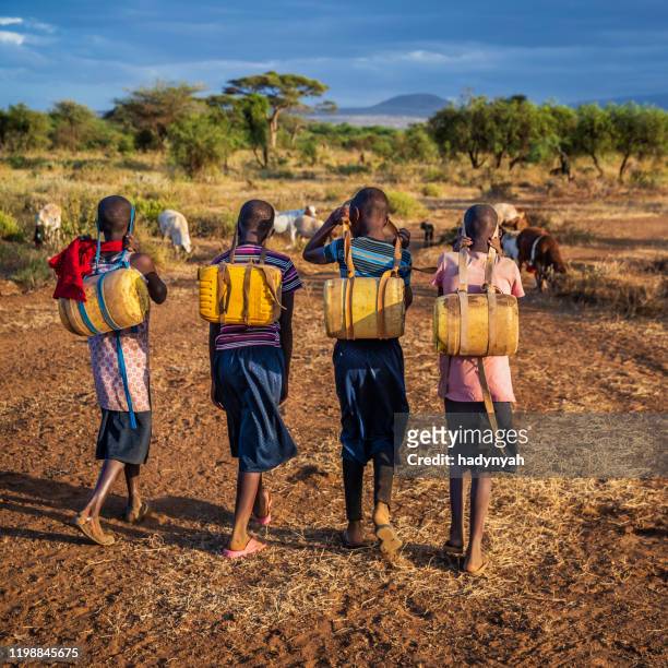 african children carrying water from the well, kenya, east africa - kenya road stock pictures, royalty-free photos & images