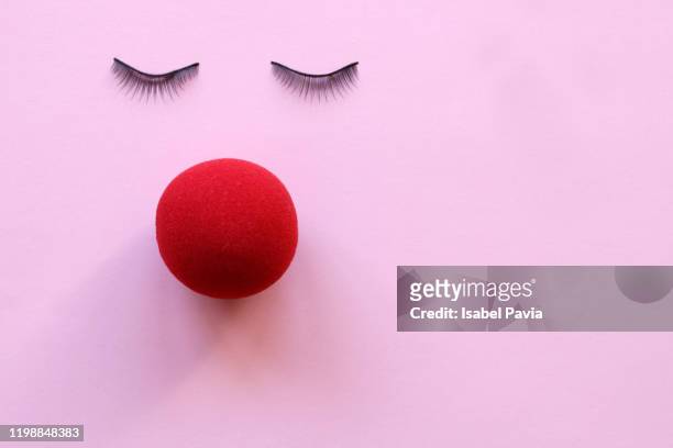 face made with eyelashes and red nose on pink background - clown imagens e fotografias de stock