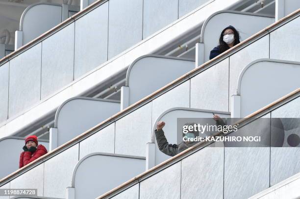 Passenger aboard the Diamond Princess cruise ship waves to the media upon arriving at Yokohama port on February 6, 2020. Ten more people on a cruise...