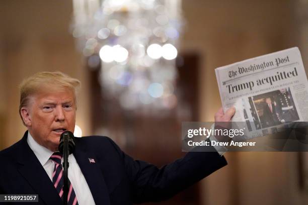 President Donald Trump holds a copy of The Washington Post as he speaks in the East Room of the White House one day after the U.S. Senate acquitted...