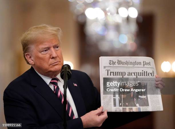 President Donald Trump holds a copy of The Washington Post as he speaks in the East Room of the White House one day after the U.S. Senate acquitted...