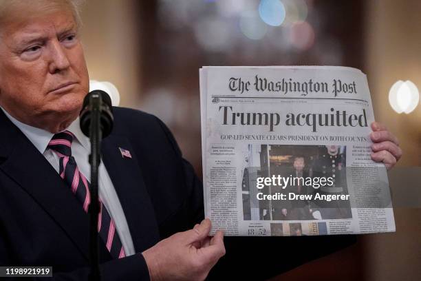 President Donald Trump holds a copy of The Washington Post as he speaks in the East Room of the White House one day after the U.S. Senate acquitted...