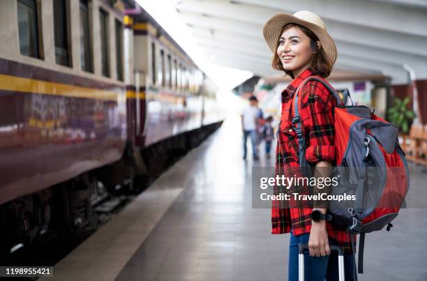 young asian woman traveler with backpack in the railway, backpack and hat at the train station with a traveler, travel concept. woman traveler tourist walking at train station - holiday asia tourist stockfoto's en -beelden