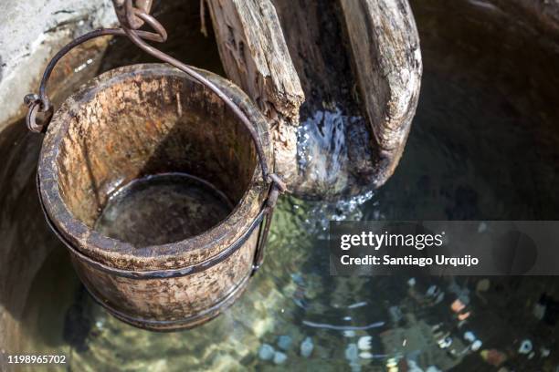 wooden bucket and gutter on a well - waterput stockfoto's en -beelden