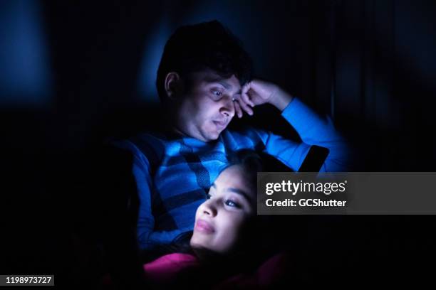 the usual routine before going to bed - young couple using smartphone in their bedroom - pleased face laptop stock pictures, royalty-free photos & images