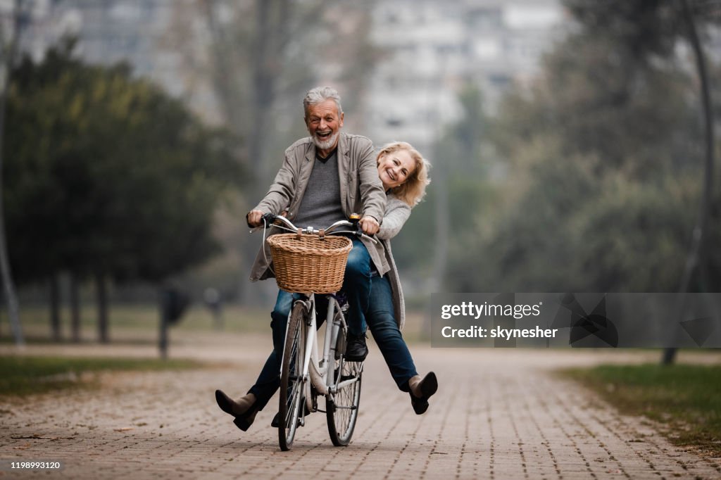 Speelse Senior paar plezier op een fiets in de herfst dag.