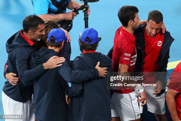 Novak Djokovic of Serbia embraces team mates after winning his final singles match against Rafael Nadal of Spain during day 10 of the ATP Cup at Ken...