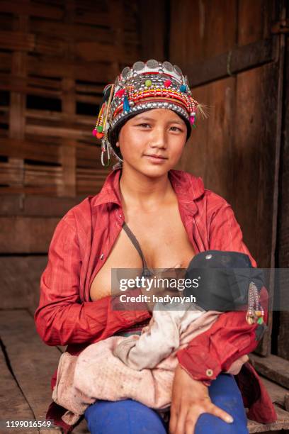 young woman from akha hill tribe breastfeeding her baby - akha woman stock pictures, royalty-free photos & images