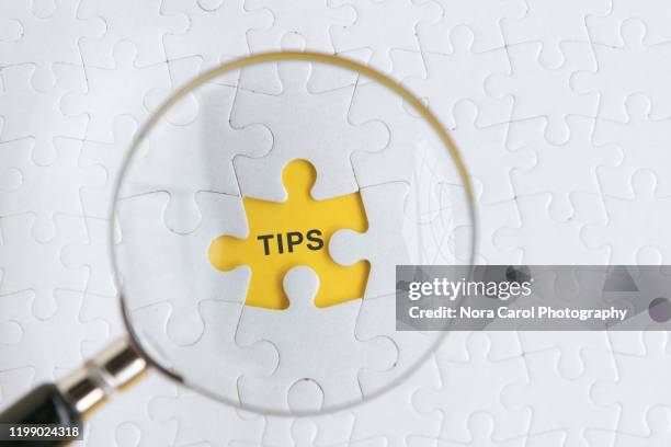 magnifying glass and tips text on puzzle piece - stunt stock pictures, royalty-free photos & images