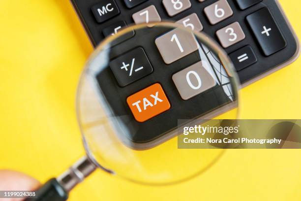 magnifying glass and tax on calculator - accounting services photos et images de collection