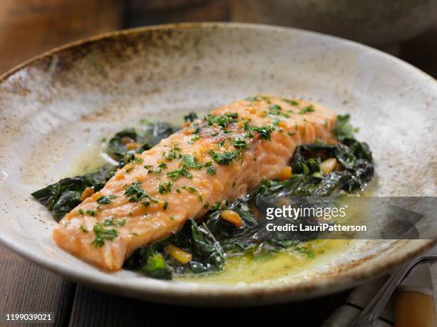 lemon, garlic and butter poached salmon with swiss chard and toasted pine nuts - baked salmon stock pictures, royalty-free photos & images