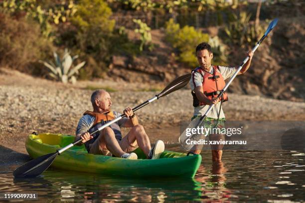 helpful friend teaching senior kayaker about paddling form - pensioners demonstrate in barcelona stock pictures, royalty-free photos & images