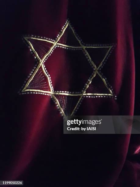 the star of david on red satin textile, vertical - judenstern stock-fotos und bilder