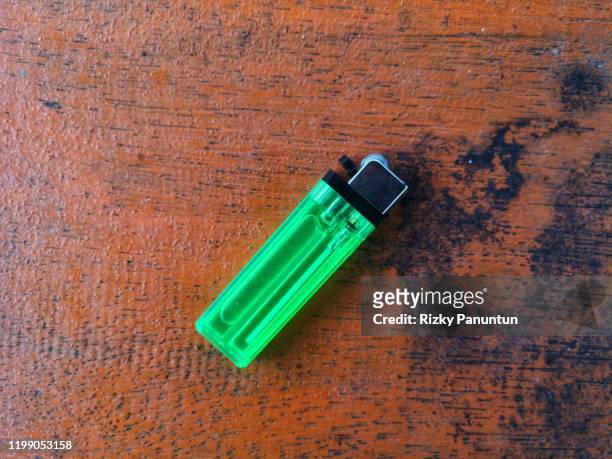 close-up of green cigarette lighter against wooden background - feuerzeug stock-fotos und bilder