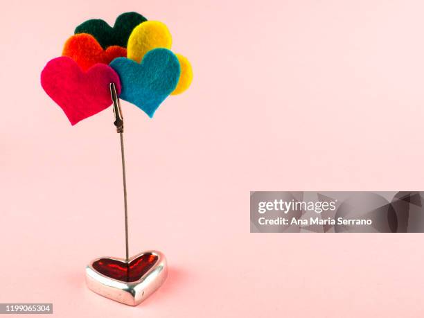 a heart-shaped ornament and a clip with several felt colored hearts. polyamory concept - poligamia fotografías e imágenes de stock