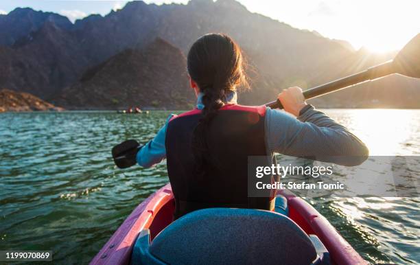 woman kayaking in hatta lake in dubai at sunset - dubai tourism stock pictures, royalty-free photos & images