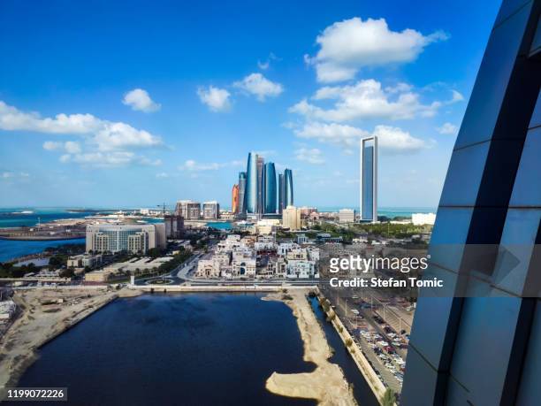 vista del horizonte de abu dabi de los edificios del centro que se elevan sobre el agua - gulf countries fotografías e imágenes de stock