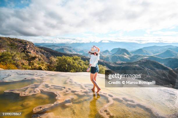 woman walking on the limestone rock formations at hierve el agua, oaxaca, mexico - beautiful mexican women stock-fotos und bilder