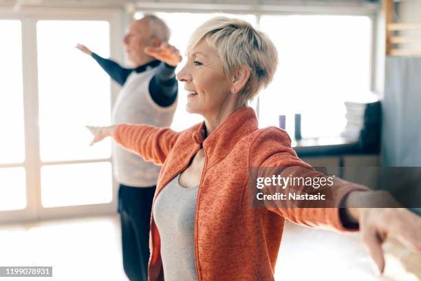 active seniors in fitness class stretching arms - boa postura imagens e fotografias de stock