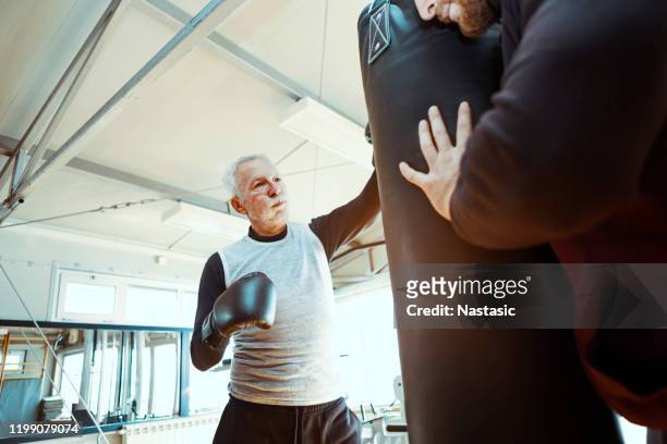 senior man in gym boxing with trainer - punching bag stock pictures, royalty-free photos & images