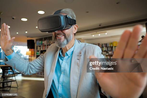 senior man using vr headset - virtual library stock pictures, royalty-free photos & images