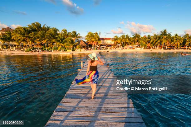 woman walking on pier to caribbean beach at sunset, mexico - cancun 個照片及圖片檔
