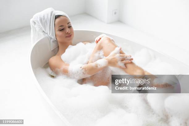 junge wunderschöne frau unter blase bad - woman bath bubbles stock-fotos und bilder