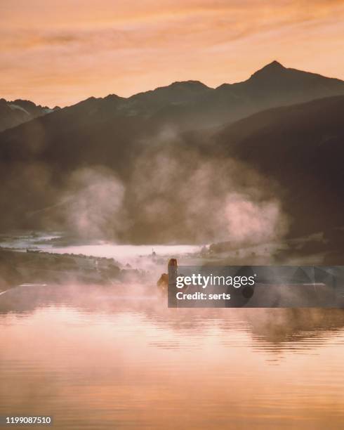 young woman relaxing in the infinity pool with a nature landscape view in dolomites, italy - infinity pool stock pictures, royalty-free photos & images