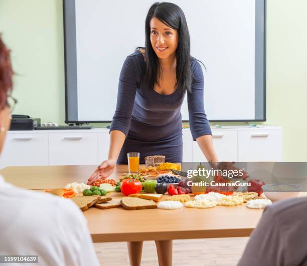 attraktive ärztin präsentiert über gesundes essen mit nahrungspyramide - lagerfoto - food pyramid stock-fotos und bilder