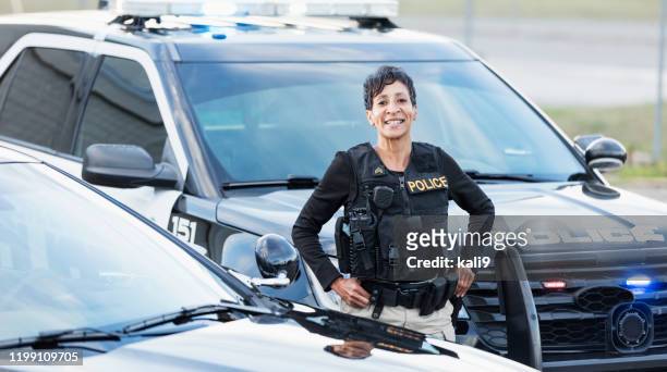 Policière afro-américaine restant par la voiture de patrouille
