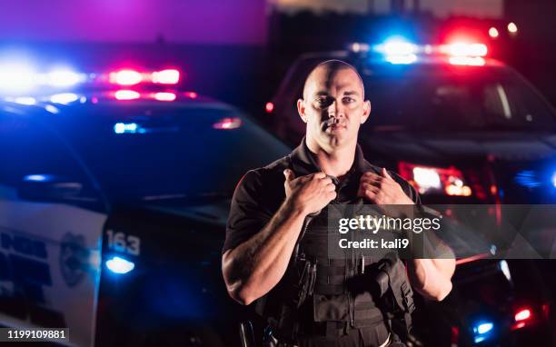 policeman wearing bulletproof vest, by patrol car - police force usa stock pictures, royalty-free photos & images