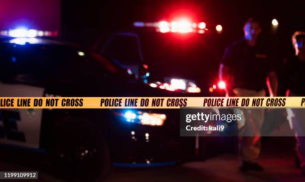 two police officers behind crime scene tape - crime tape stock pictures, royalty-free photos & images