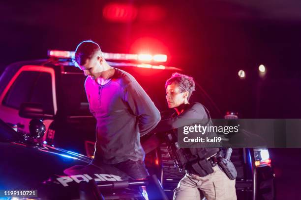 policewoman putting handcuffs on suspect - mulher polícia imagens e fotografias de stock