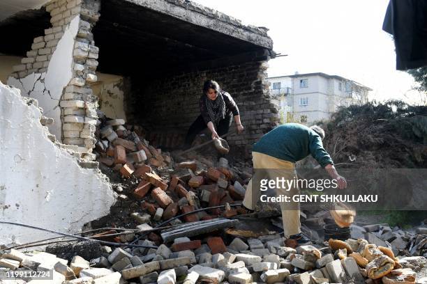 Vjollca Mesiti and Meleq Mesiti rummage through the ruins of their bakery to salvage bread baking pans in Thumane, northwest of the capital Tirana,...