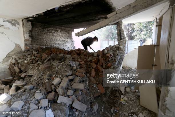 Vjollca Mesiti rummages through the ruins of her bakery to salvage bread baking pans in Thumane, northwest of the capital Tirana, on January 31,...