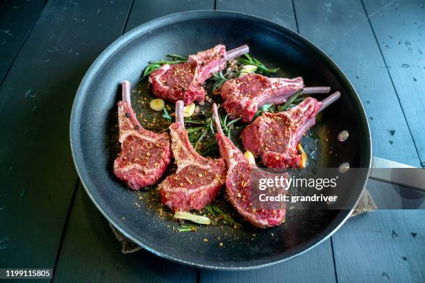 chuletas de cordero crudas en una sartén listo para ser cocinado con ajo, puerros y romero como condimento - chuleta fotografías e imágenes de stock