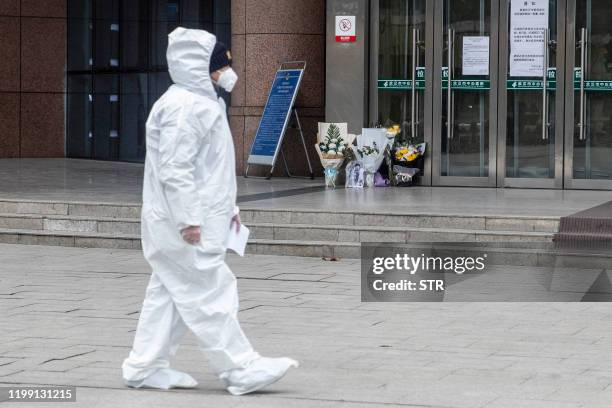 Medical staff member walks past a flower tribute to the late ophthalmologist Li Wenliang at the Houhu Branch of Wuhan Central Hospital in Wuhan in...