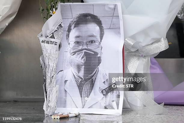 Photo of the late ophthalmologist Li Wenliang is seen with flower bouquets at the Houhu Branch of Wuhan Central Hospital in Wuhan in China's central...