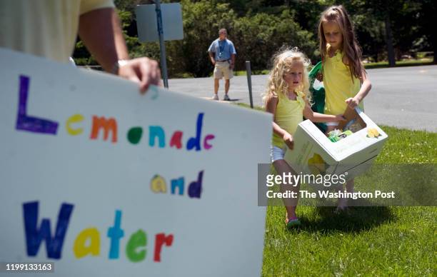 Sofia Fernandez right, helps her sister Alina Fernandez move their lemonade stand 50 feet from the corner of River and Harrington Dr. On Friday, June...