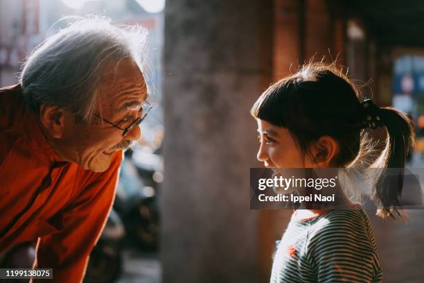 cute little eurasian girl smiling at japanese grandfather with sunlight - japanese ol stockfoto's en -beelden