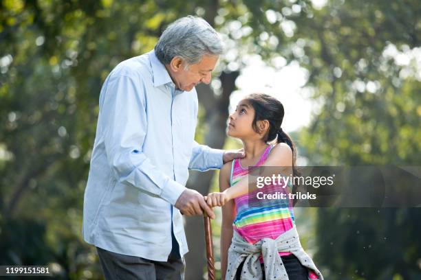 ragazza felice che si tiene per mano il nonno al parco - nonni bastone foto e immagini stock
