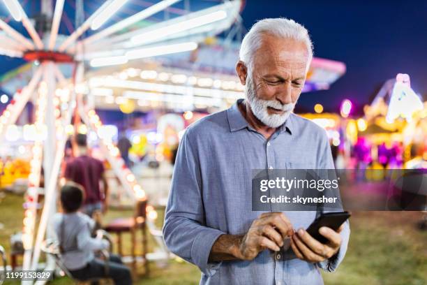 happy mature man using cell phone at amusement park. - white nights festival imagens e fotografias de stock