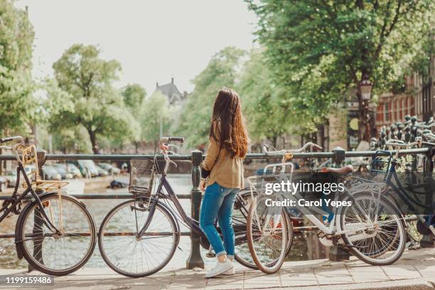 young female traveler exploring amsterdam canals - amsterdam bike stock-fotos und bilder