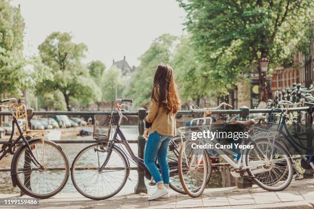 young female traveler exploring amsterdam canals - amsterdam mensen boot stockfoto's en -beelden